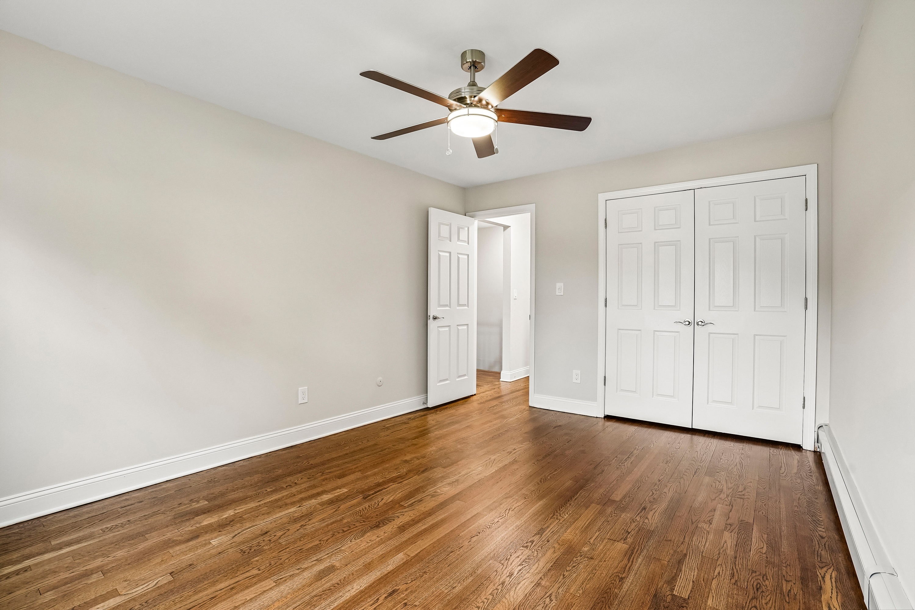 A room with a ceiling fan and wooden floors.